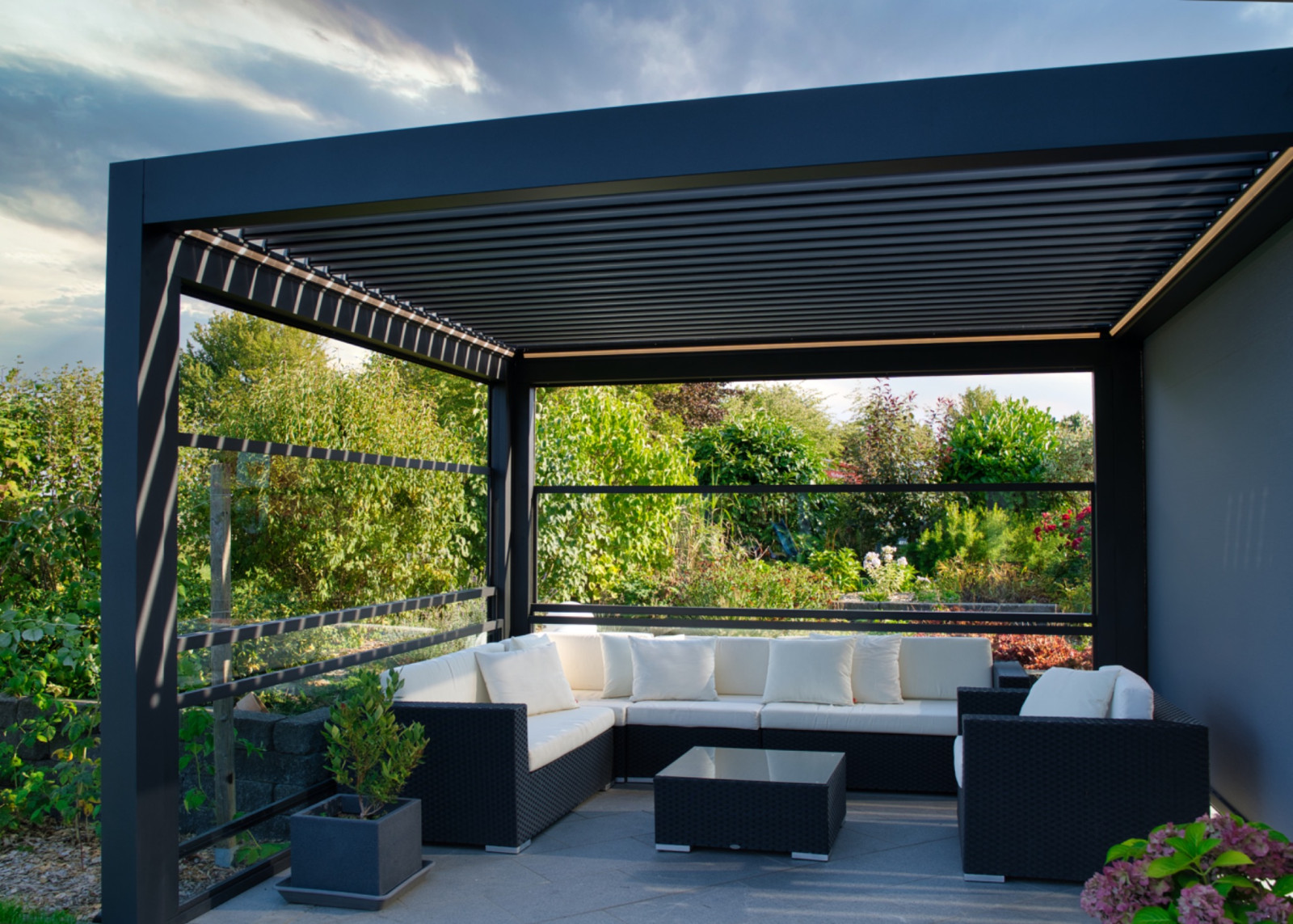 Elegant outdoor living space with black furniture, featuring a Palmiye pergola and shading system for improved comfort and quality.