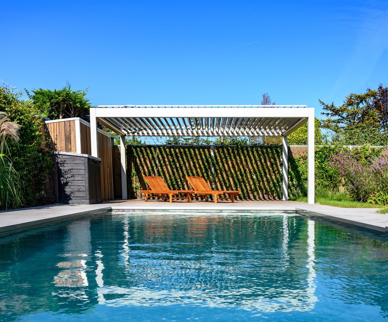 A tranquil poolside scene showcasing Palmiye Global's modern pergola alongside comfortable lounge chairs.