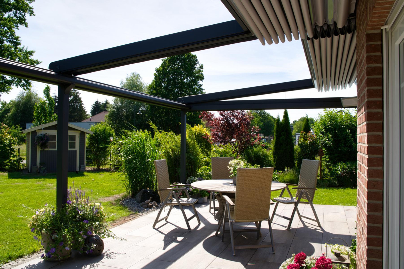Outdoor patio with a table and chairs sheltered under a covered pergola designed by Palmiye Global.