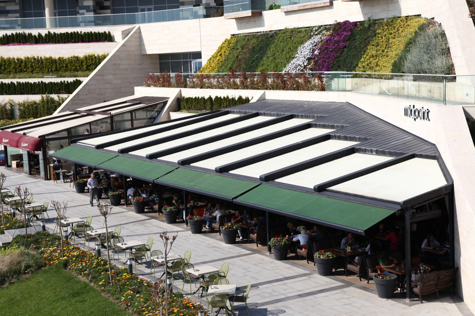 A large building featuring a green roof, showcasing outdoor pergola designed by Palmiye Global, enhances brand image.