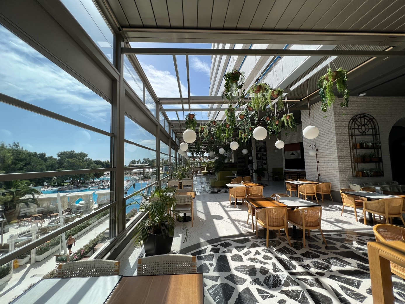 Palmiye Global pergola sistemi altında masa ve sandalyelerin yer aldığı bir çatı restoranı, açık havada yemek keyfi sunuyor.