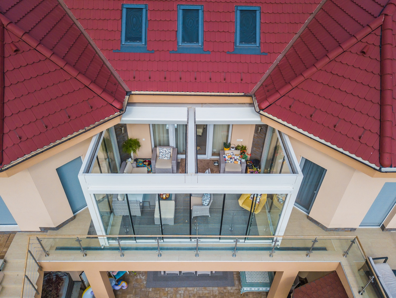 A house featuring a red roof and glass walls, complemented by a wind-resistant pergola system by Palmiye Global.