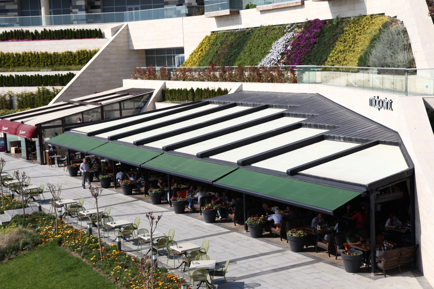 Large-scale cassette awning and pergola system providing functional shading for a commercial outdoor terrace