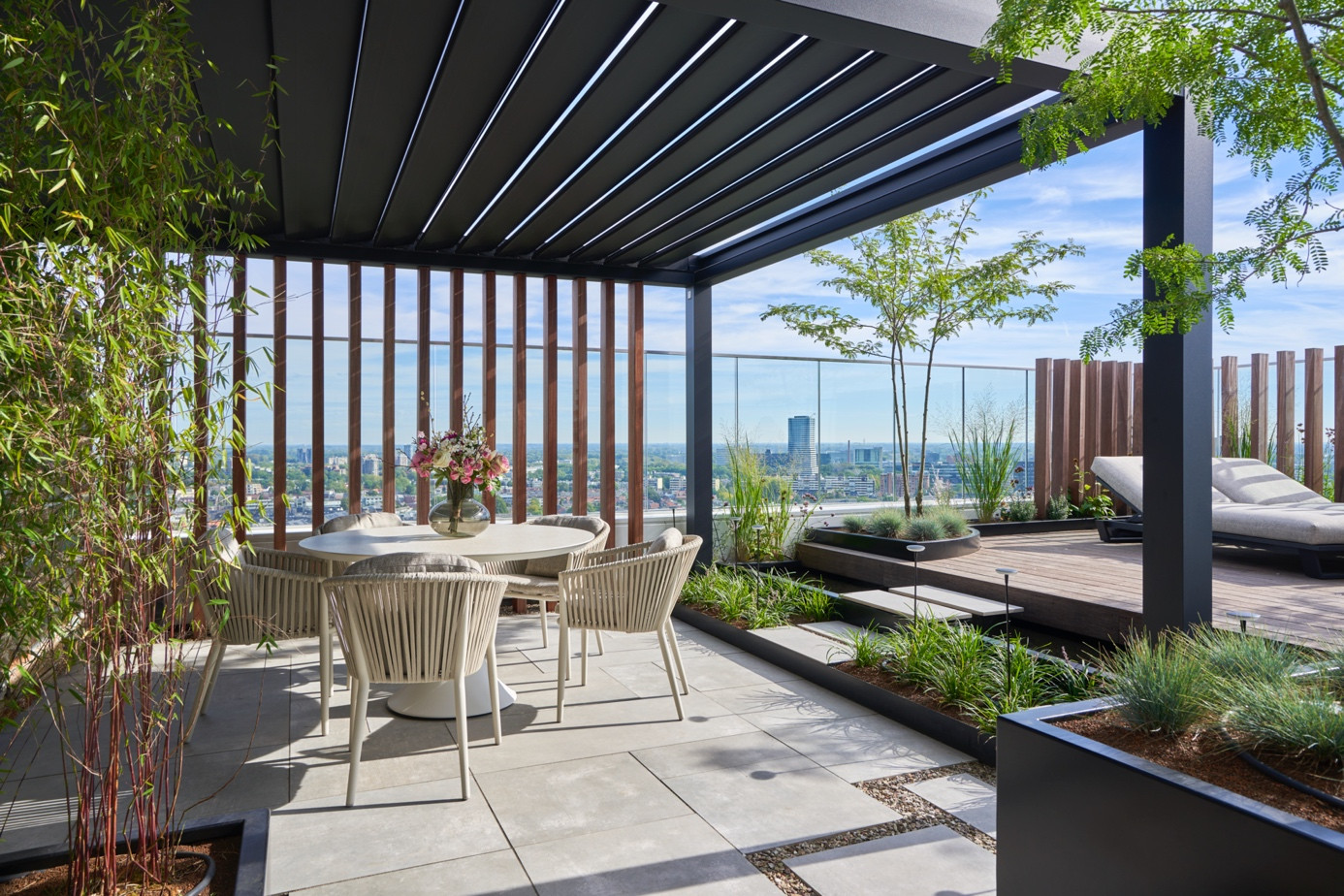 Black bioclimatic pergola system shading a rooftop terrace with city views